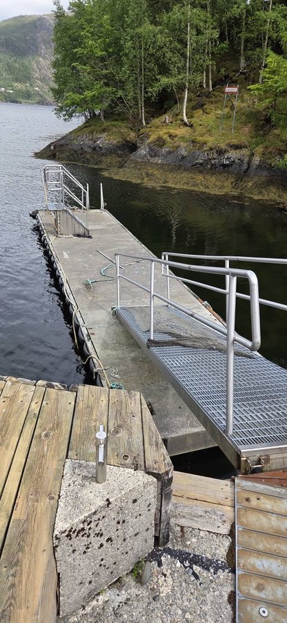Flytebrygge med rekkverk og landgang ved en holme
